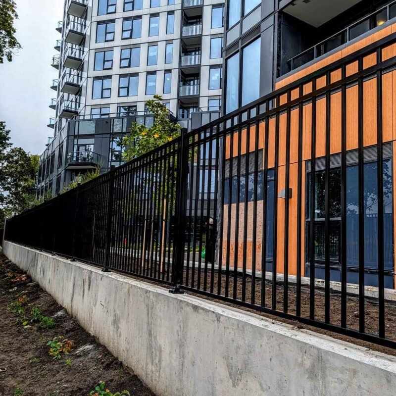 Black aluminum picket fence installed on concrete retaining wall