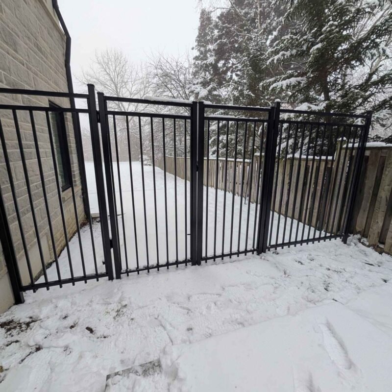 Black aluminum picket fence gate in winter