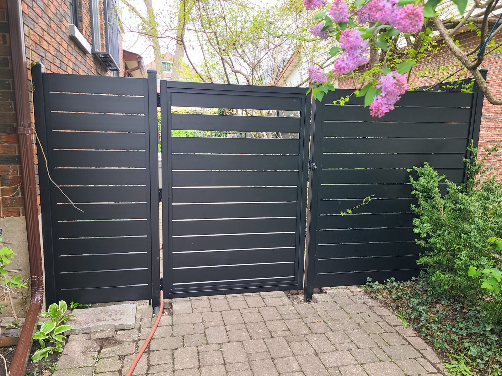 Black aluminum horizontal slat fence panels in landscaped yard