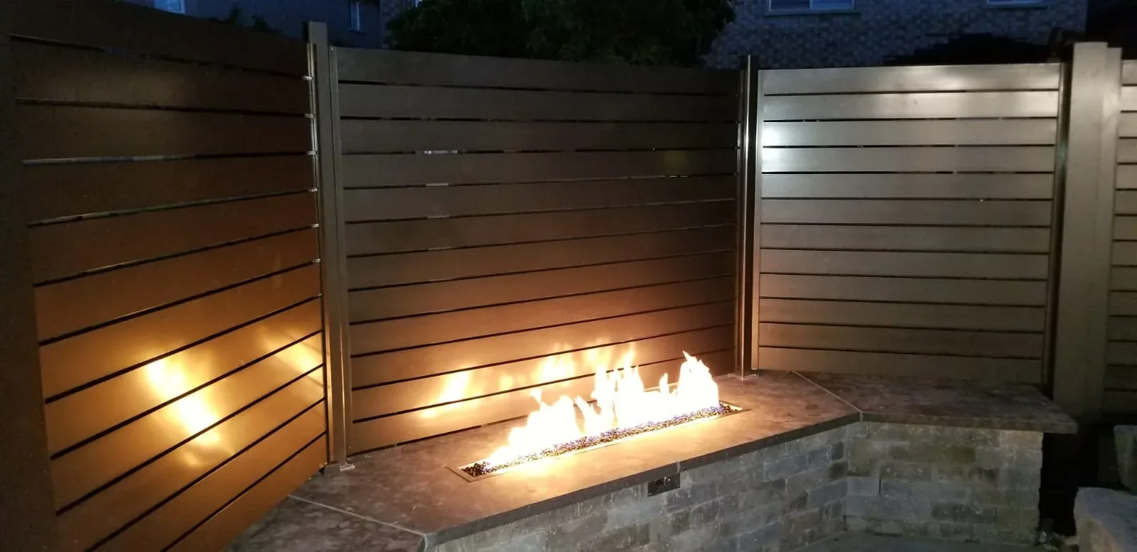 Black aluminum horizontal fence panels behind an outdoor fire feature
